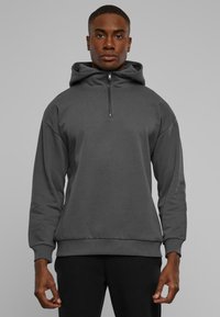 Mørkegrå zip-up hoodie lavet af glat stof, med hætte, lange ærmer og ribbede mansjetter og kant. Standard pasform med afslappet design.
