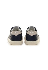 Sneaker in pelle blu navy con accenti beige, dettaglio bianco "1967" sul tallone e suola color crema. Texture liscia e design minimalista.