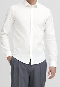 Witte lange mouwen shirt gemaakt van een gladde stof, met een klassieke kraag, knoopsluiting en een gebogen zoom, gecombineerd met grijs gestreepte broek.
