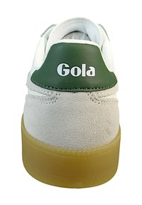Zapatilla blanca y gris con un tab de talón de cuero verde marcado "Gola." Presenta una parte trasera de ante texturizado y una suela de goma.