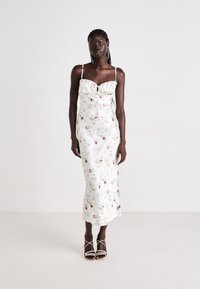 Abito in satin floreale con spalline sottili, scollatura arricciata e orlo dritto. Caratterizzato da una base bianca con motivi di rose colorate.