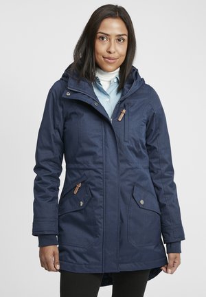 Marineblauwe parka met capuchon, ritssluiting, textuurstof, twee voorzakken en leren accenten op de ritsen en zakken.