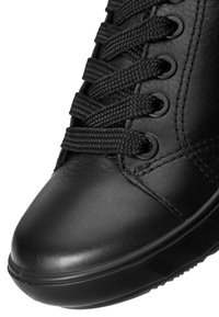 Nahaufnahme der schwarzen Leder-Sneaker-Spitze mit dicken schwarzen Schnürsenkeln, die durch sechs Ösen an der Seite gefädelt sind.