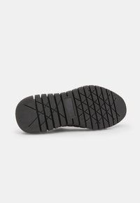 Semelle de chaussure en caoutchouc noir avec une surface texturée, présentant un motif de semelle composé de lignes horizontales et verticales pour une meilleure adhérence.
