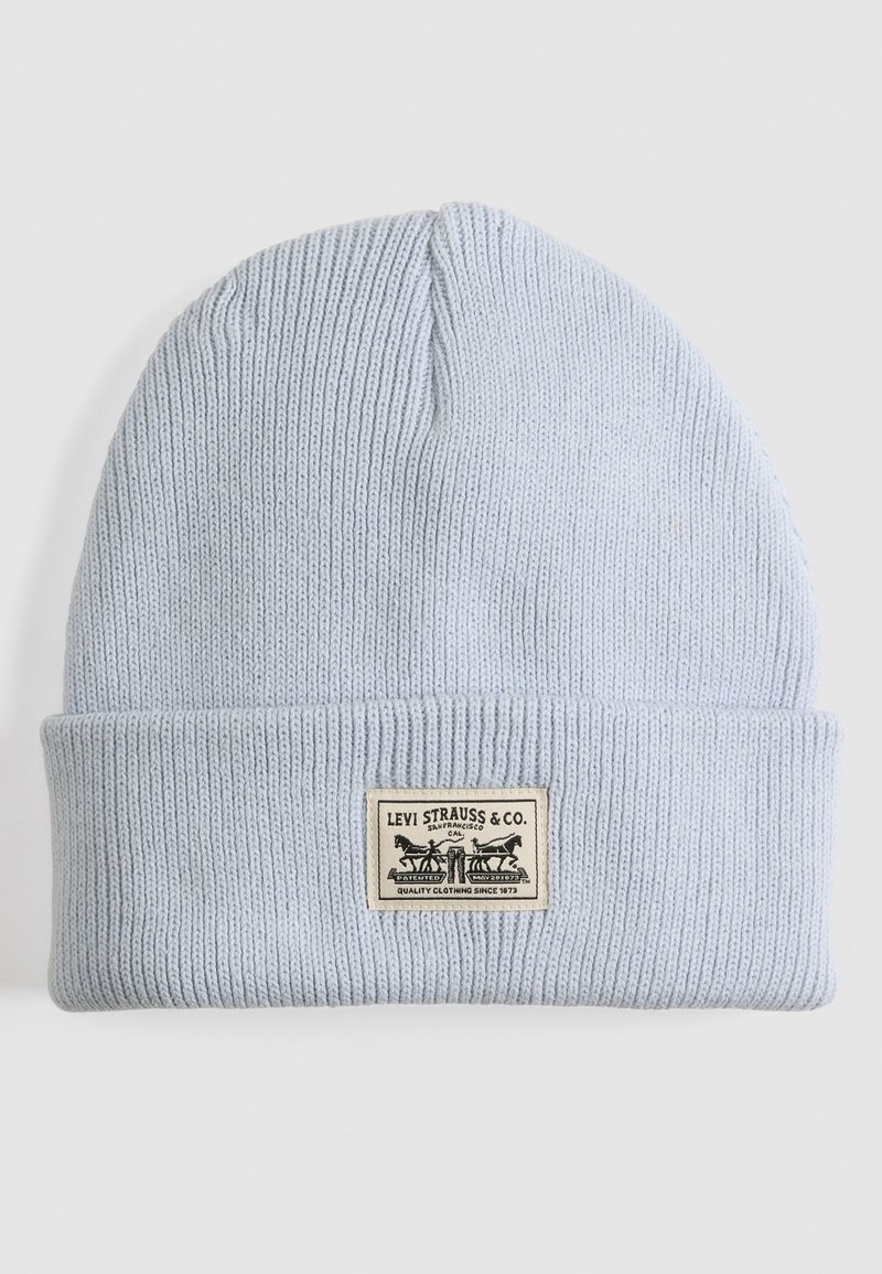 Gorro de punto azul claro con un dobladillo. Cuenta con una etiqueta de tela rectangular impresa con el logotipo de Levi Strauss & Co. y texto.