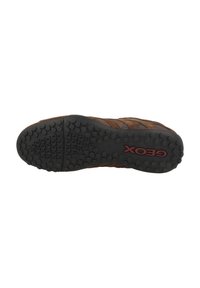 Sneaker marrone con una superficie testurizzata, suola in gomma con motivi circolari di presa e un logo "Geox" rosso ben visibile.