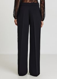 Pantaloni neri a gamba larga con una trama liscia, caratterizzati da una vita alta e pieghe frontali. Nessun ornamento o motivo visibile.