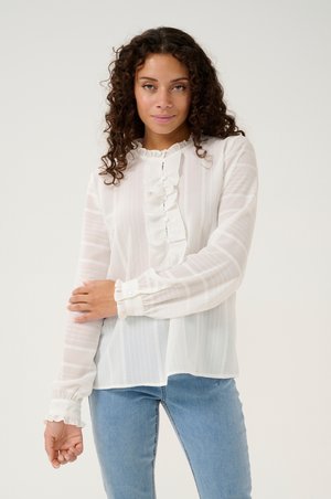White, long-sleeve blouse with a ruffled neckline and button placket, featuring subtle vertical stripes and gathered cuffs.