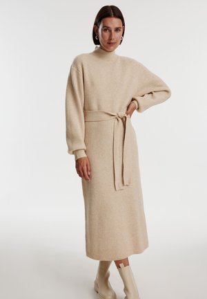 Beiges Rippstrickkleid mit hohem Hals und langen Ärmeln, tailliert mit einem passenden Bindegürtel. Hat eine gerade Silhouette.