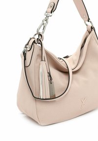Sac à main perforé rose clair avec des bords noirs, design flexible, quincaillerie en argent et détail à frange. Comprend une seule sangle ajustable.