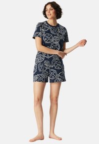 Katoenen pyjamastel met een marineblauwe basis en een wit sterren- en cirkelpatroon, korte mouwen en shorts, ontworpen voor comfort.
