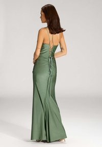 Robe de soirée en satin vert avec une silhouette ajustée, détail de corsage lacé au dos et bretelles réglables, dotée d'une jupe fluide et d'une texture lisse.