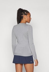 Sivi dolg rokav sv sweater z okroglo izrezom, slim fit in rebrastimi manšetami, v kombinaciji z mornarsko modro krilo z logotipom.
