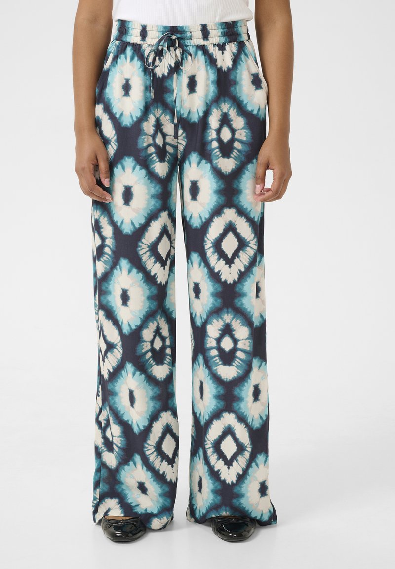 Tumedate voolavad püksid sinise ja kreemika geomeetrilise mustriga; elastne vöökoht koos paelaga; laiad sääred.