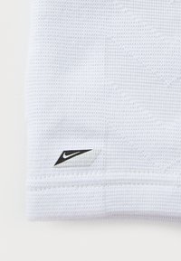 Tissu athlétique blanc avec un motif texturé. Présente un accent du logo Nike noir dans le coin inférieur.