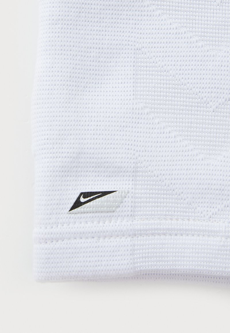 Witte sportieve stof met een gestructureerd patroon. Heeft een zwart Nike-logoaccent in de onderste hoek.