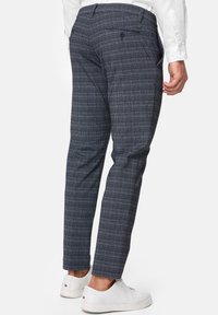 Skreddersydde rutete bukser i mørkeblått med hvite og røde linjer; har en slim fit, lommer og et strukturert stoff. Stylet med hvite joggesko.