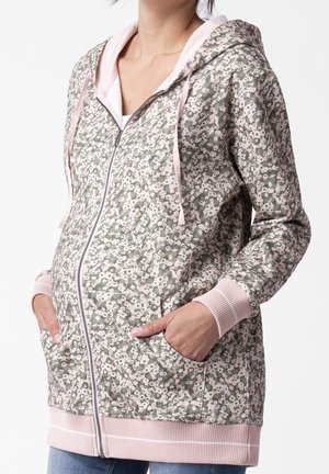 Hoodie zippé à motif floral en vert et rose. Présente une texture douce, des poches avant et des poignets et un ourlet côtelés. Légère avec une capuche.