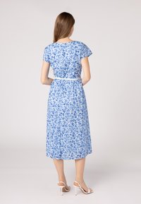 Abito midi floreale in azzurro chiaro, realizzato in tessuto leggero. Presenta maniche corte, una vita aderente con una cintura bianca e una gonna fluida.
