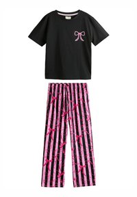 Svart bomull T-shirt med en rosa rosett-design på bröstet, kombinerad med rosa och svarta randiga byxor med rosett-mönster.