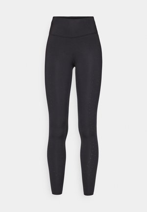 Leggings pretos feitos de material elástico, com uma cintura alta, textura suave e pequenas perfurações ao longo das pernas externas.
