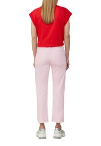Top corto rosso a maniche corte abbinato a jeans dritti rosa chiaro. Footwear presenta accenti grigi. Design semplice senza fantasie o decorazioni.