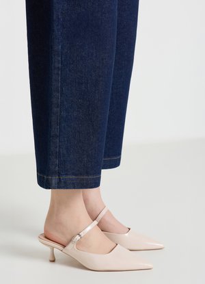 Hellrosa Slingback-Pumps mit spitzen Zehen und einem dünnen Knöchelriemen, kombiniert mit dunkelblauen, verkürzten Jeans. Glatte, glänzende Textur.