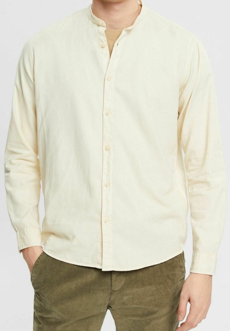 Camicia a maniche lunghe color crema chiaro con colletto alla mandarina, patta con bottoni, morbida texture di cotone e vestibilità leggermente rilassata.