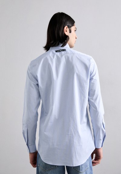 Gestreept shirt in lichtblauw en wit, met lange mouwen en knoopmanchetten. Bevat zwart "MOSCHINO" logo op de achterkant van de kraag.