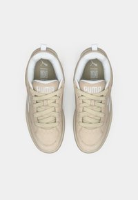 Baskets en daim beige avec accents blancs, bout rond, lacets plats, col matelassé et semelle texturée. Logo affiché sur la languette et le côté.