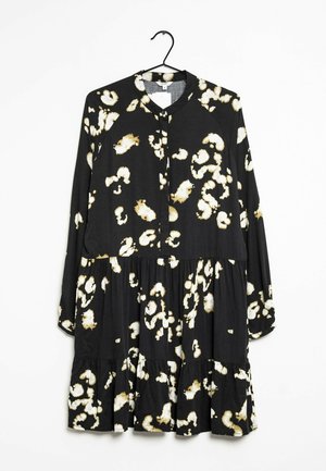 Black dress with long sleeves, featuring a tiered design and white leopard print pattern. Made of lightweight fabric with a buttoned neckline.