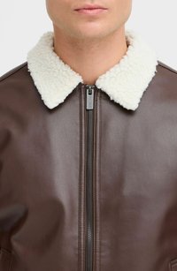Chaqueta de cuero marrón con un suave cuello crema, cierre frontal con cremallera y textura lisa. Sin patrones visibles ni detalles de herrajes.