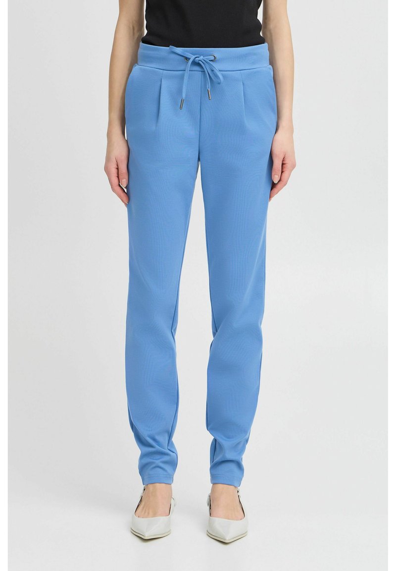 Pantalones de chándal azul claro, ajustados, con cintura elástica, cordón y detalles plisados. Textura suave y tela elástica.