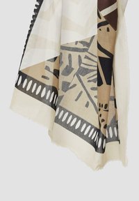 Écharpe à motifs en tissu tissé de couleur crème, beige et noir. Présente des formes géométriques et une bordure décorative avec des découpes ovales.