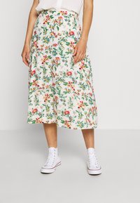 Jupe midi florale avec une base blanche et des fleurs multicolores, au design évasé et une taille. Associée à des baskets montantes blanches.