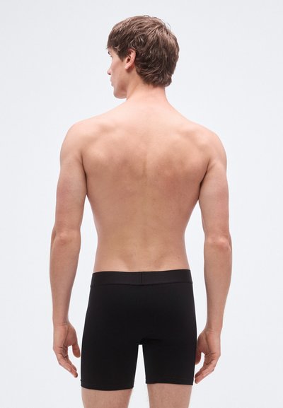 Calzoncillos bóxer negros hechos de tela suave, con una cinturilla cómoda y un ajuste ceñido, mostrando un diseño sencillo sin patrones ni adornos.