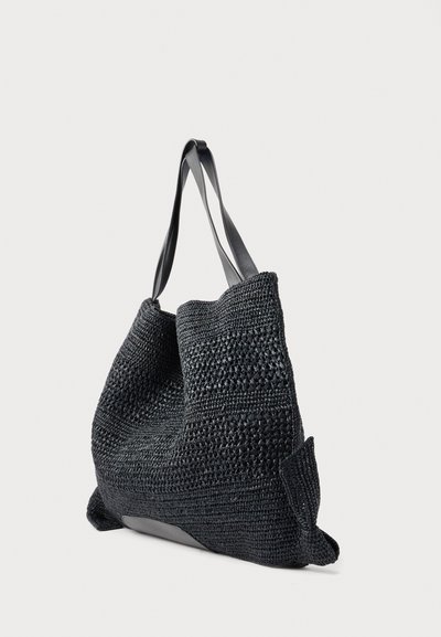 Μαύρη υφασμένη τσάντα ώμου με δύο λείες μαύρες λαβές και ευέλικτο, υφασμένο σώμα σε απλό φόντο.