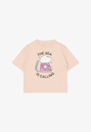 Lyserød T-shirt med korte ærmer lavet af blødt stof med en illustration af en telefon med skyer og teksten "HAVET RINGER."