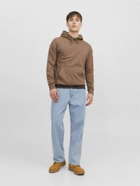 Brun hoodie med justerbar dragsko, känguruficka, kombinerad med ljusblå jeans med raka ben och bruna arbetsstövlar.