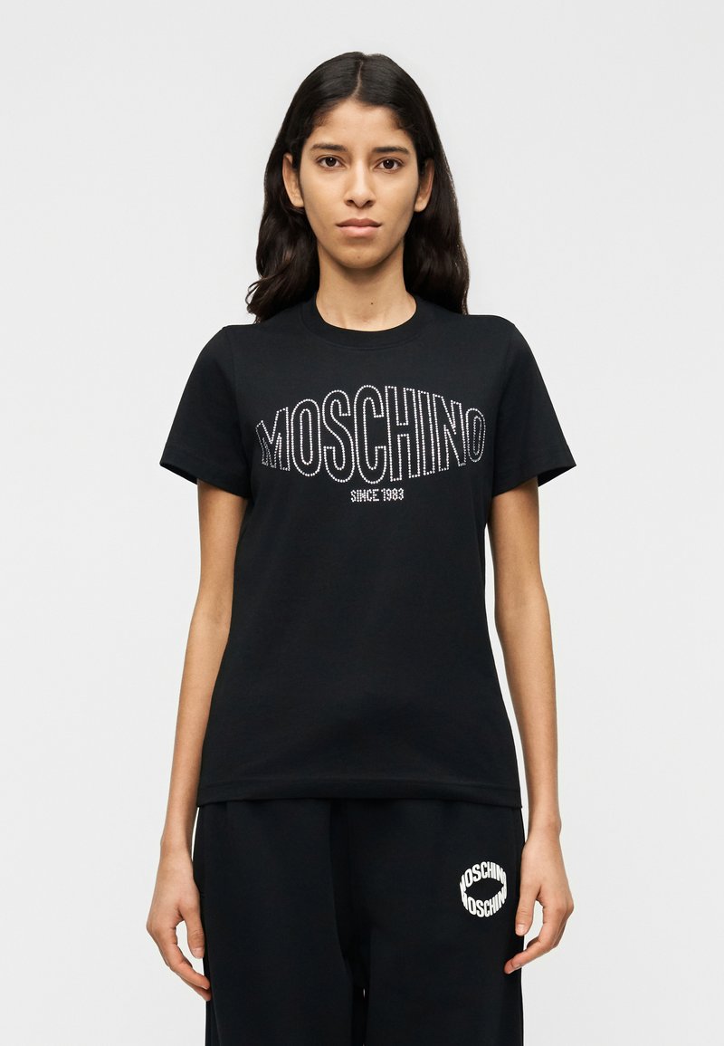 Μαύρο βαμβακερό t-shirt με το λογότυπο "MOSCHINO" σε στρας και το κείμενο "SINCE 1983". Κλασικός στρογγυλός λαιμός και κοντά μανίκια. Απλός σχεδιασμός.
