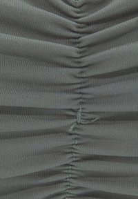 Tessuto grigio con texture arricciata; le pieghe verticali creano un effetto ondulato. Lucentezza leggera visibile, i dettagli di cucitura aggiungono un design strutturato.