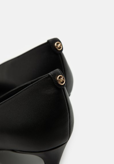 Chaussures à talons hauts noires avec une texture en cuir lisse, présentant des accents de logo doré à l'arrière et un design à bout pointu.