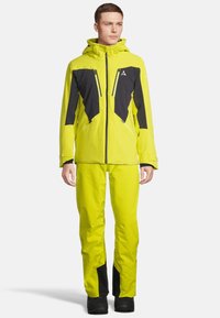 Helle gelbe Skijacke und -hose mit schwarzen Akzenten, ausgestattet mit einem Reißverschluss vorne, Kapuze und mehreren Taschen. Glattes, wasserdichtes Material.