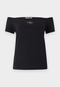 Juoda off-the-shoulder marškinėliai, pagaminti iš medvilnės, su trumpomis rankovėmis. Priekyje yra mažas pilkas Calvin Klein logotipas.