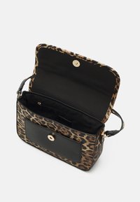 Pieni leopardi-kuosisy tote-laukku, jossa on musta etutasku ja kultainen napsulukko. Laukun läppä on avattuna, ja sisäpuolelta löytyy vetoketjullinen osio.