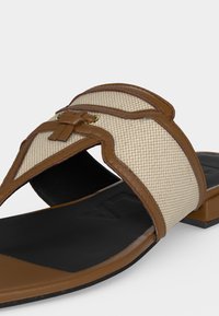 Καφέ και μπεζ σανδάλι slip-on με πλεκτό υφαντό επάνω μέρος, δερμάτινη επένδυση και διακοσμητική λεπτομέρεια κόμπου σε μαύρη σόλα και χαμηλό τακούνι.