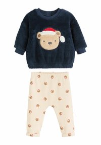Marinblå fluffig topp med björns ansikte och tomteluverdesign; beige ribbade byxor med upprepade pepparkaksdekorer och uppvikta manschetter.