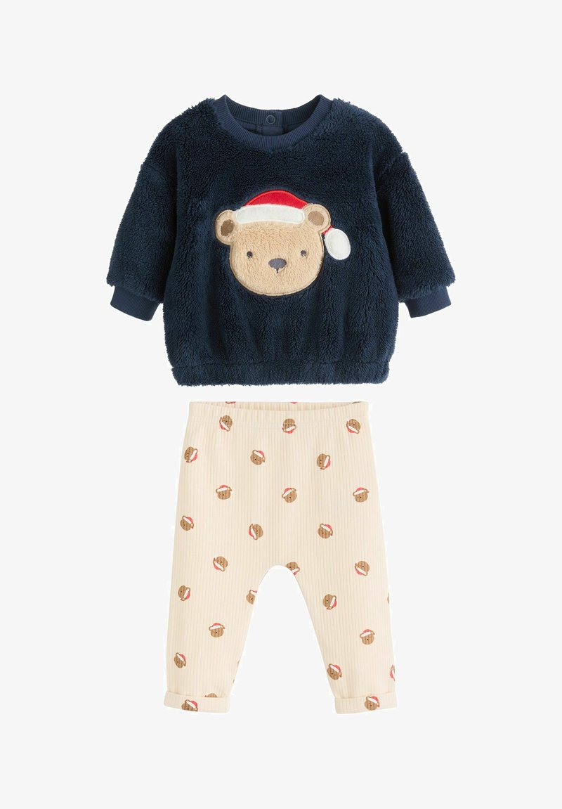 Tengerészhaditengerészeti bolyhos felső, medve arcával és Mikulás sapkás mintával; bézs bordázott alsó, ismétlődő mézeskalács mintákkal és felhajtott szegélyekkel.