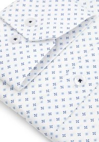 Biała koszula z geometrycznym niebieskim wzorem, posiadająca średniej wielkości guziki i gładką teksturę. Widoczne są złożone kołnierz i rękawy.