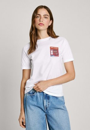 T-shirt en coton blanc avec un patch graphique coloré portant le texte "PEPE JEANS", à manches courtes et coupe décontractée. Porté avec un jean en denim bleu.